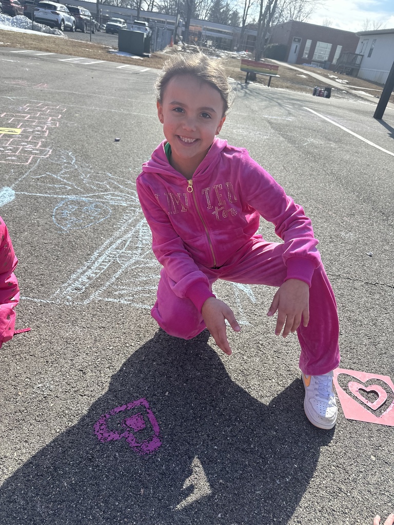 A student poses with chalk art drawn for Kindness Week.