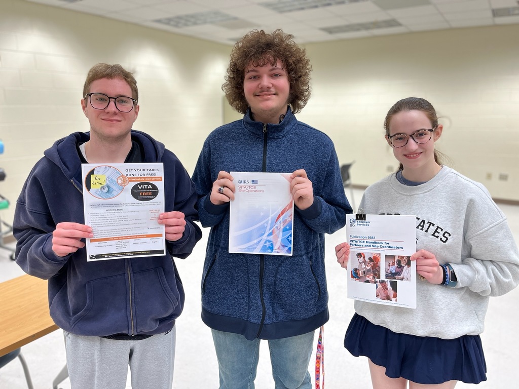 Three students pose for a photo while holding fliers related to offering free tax preparation. 