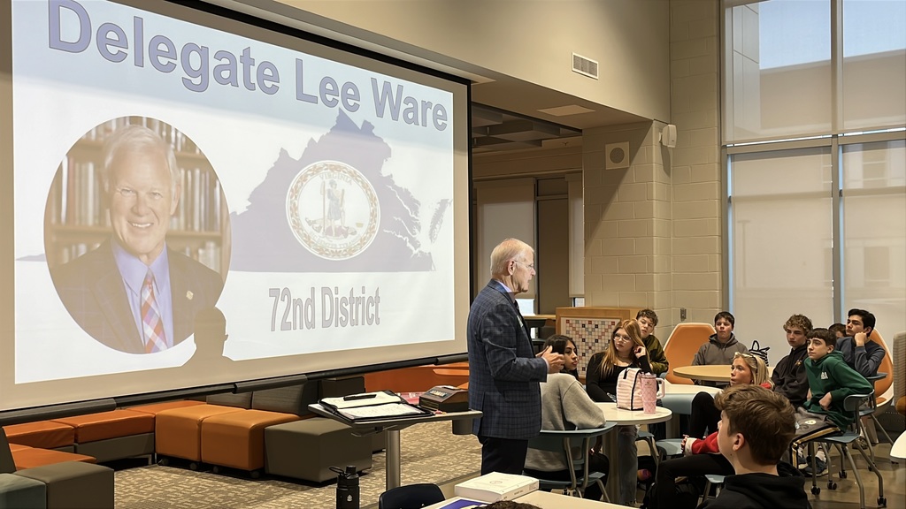 A politician speaks to a group of students in a middle school library.