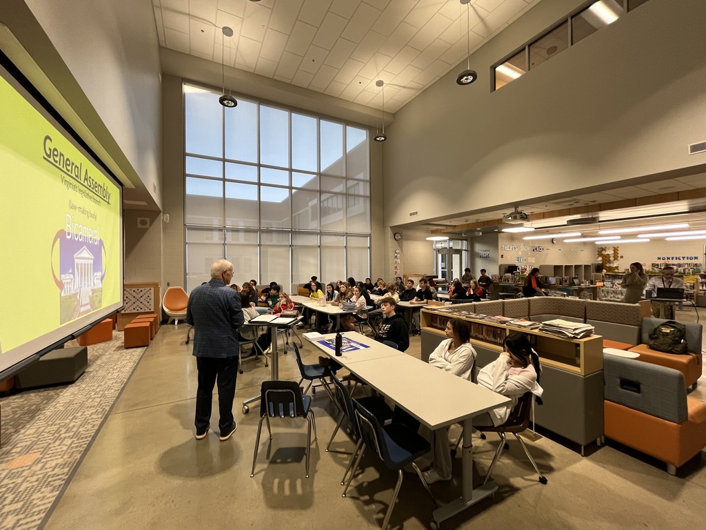 A politician speaks to a group of students in a middle school library.