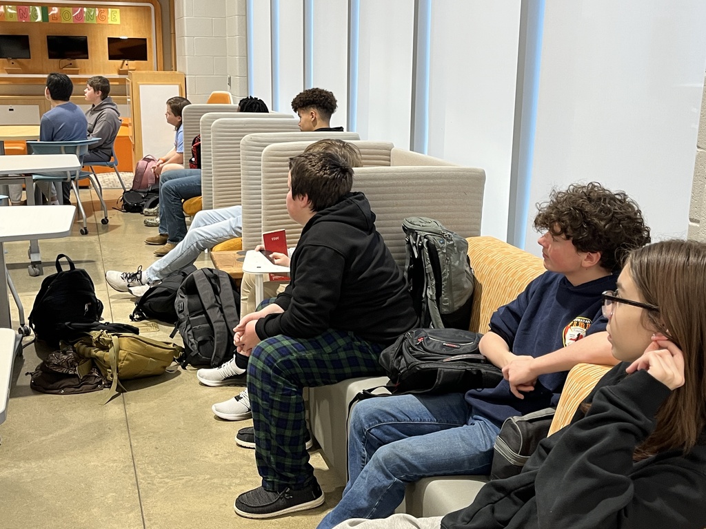 Students in a middle school library listen to a guest speaker.