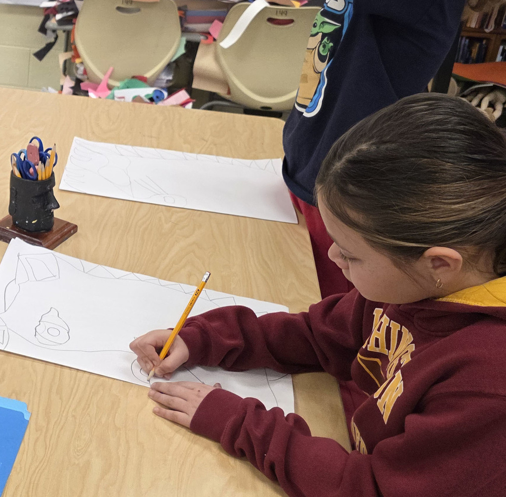 A student in art class draws a ceremonial mask inspired by an African tribe.