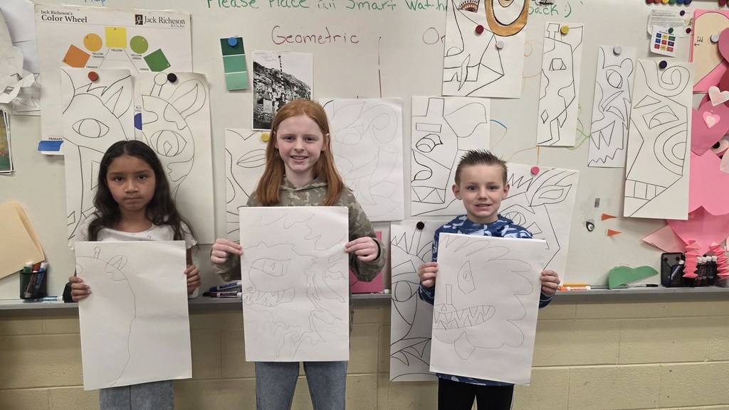 Students in art class show drawings of ceremonial masks they created inspired by an African tribe.