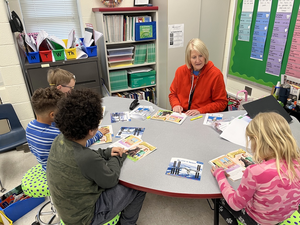 Students read books with a teacher at a literacy station tied to the soft c.