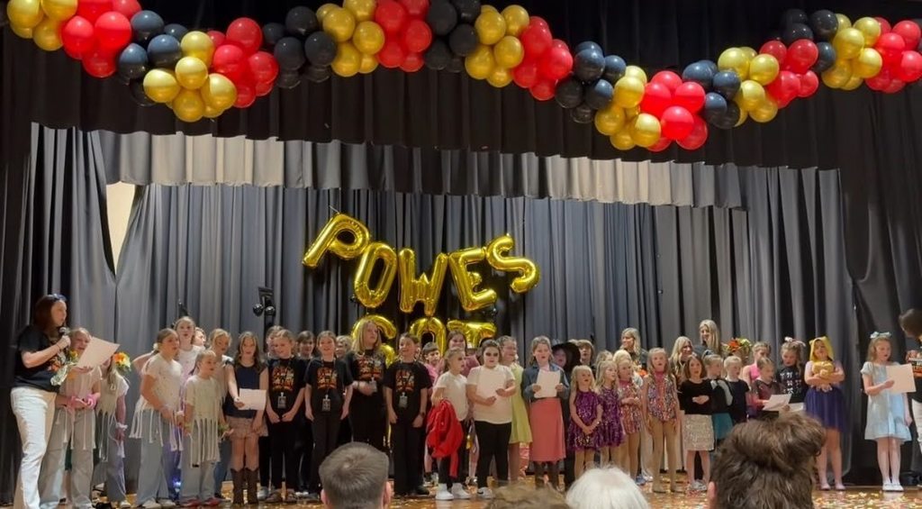 A large group of student performers pose for photo at a talent show.