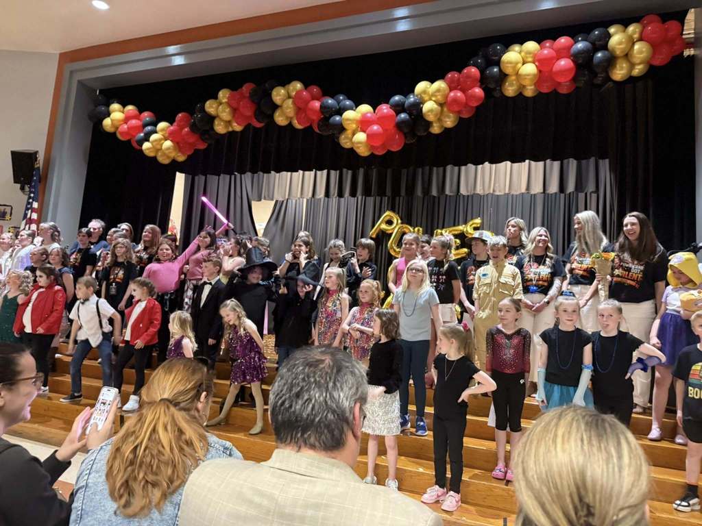 A large group of student performers pose for photo at a talent show.
