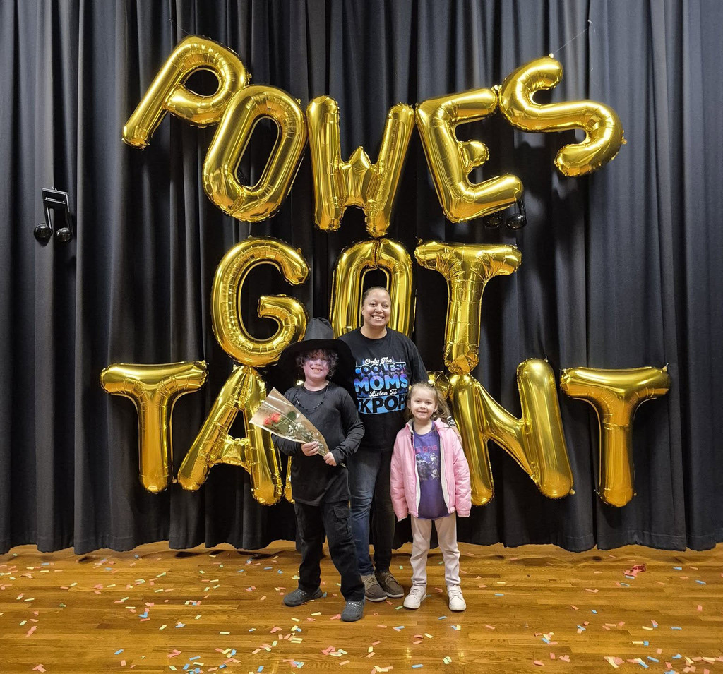 Student performers and an adult pose for photo at a talent show.