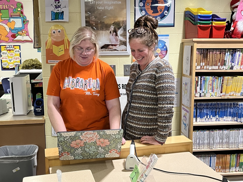 Two women look at a laptop and smile.
