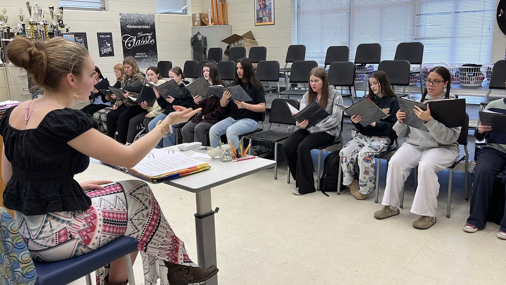 A senior participating in a Teacher for a Day activity conducts fellow students in chorus class.