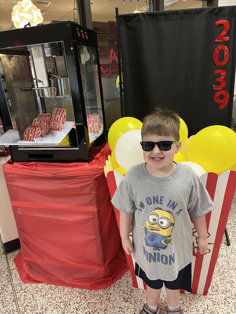 A child poses for a photo in front of a kindergarten registration day backdrop.