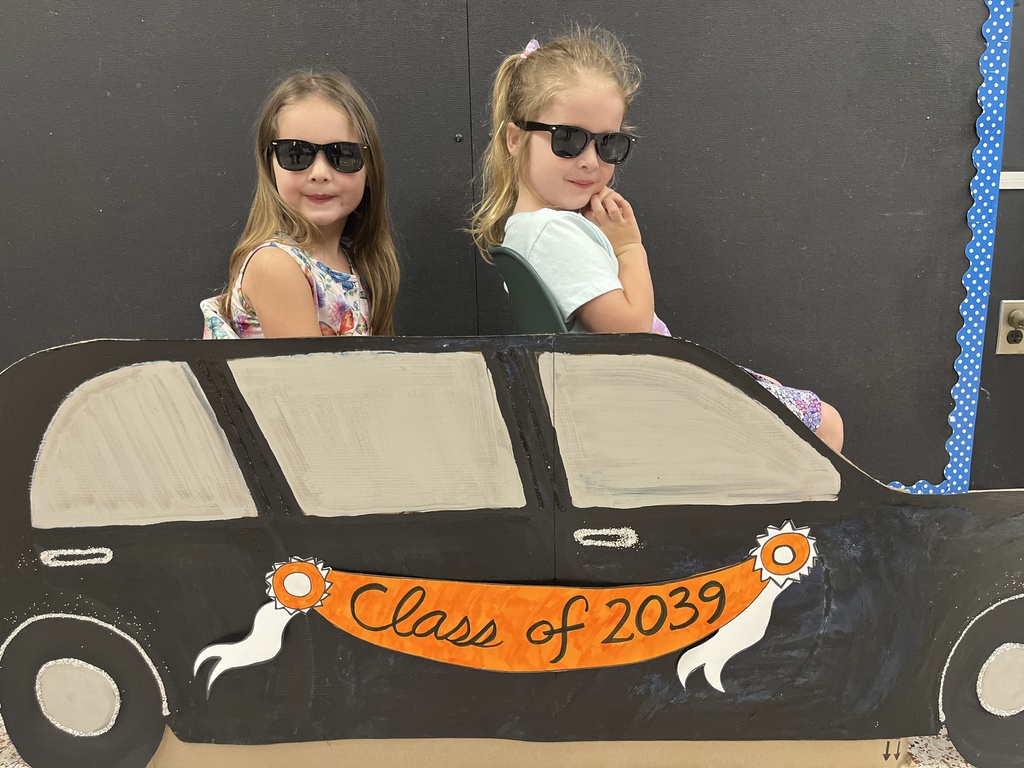 Two children  pose for a photo in front of a kindergarten registration day backdrop.