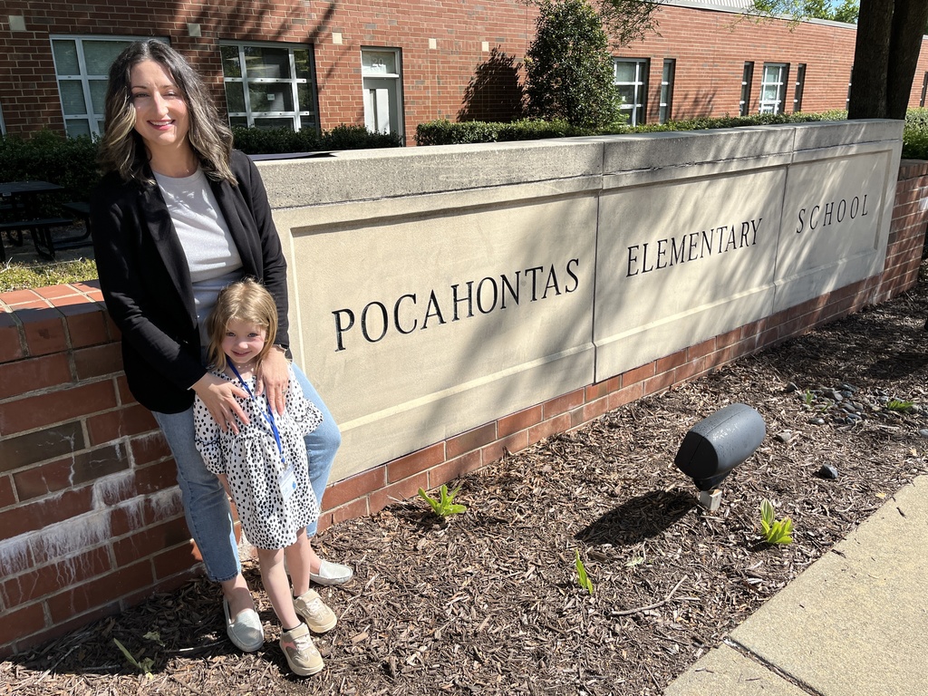 An adult and a child pose for a photo in front of the Pocahontas Elementary School sign.