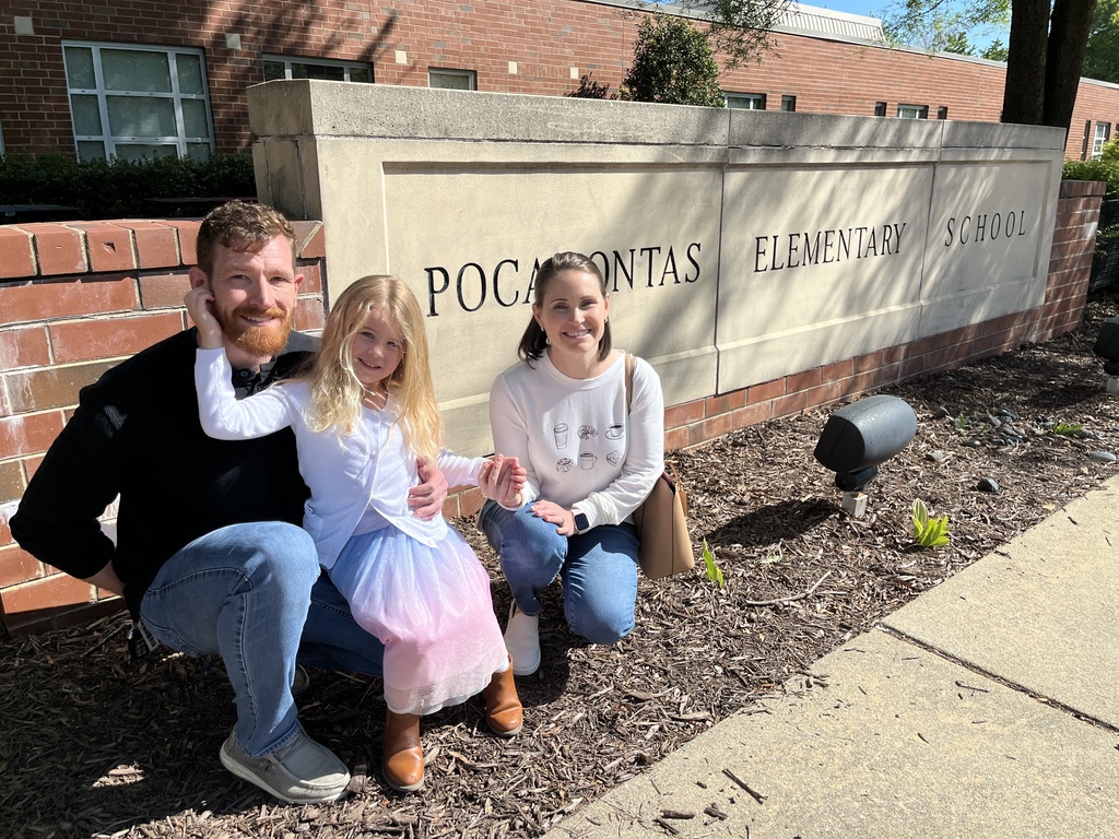 Two adults and a child pose for a photo in front of the Pocahontas Elementary School sign.