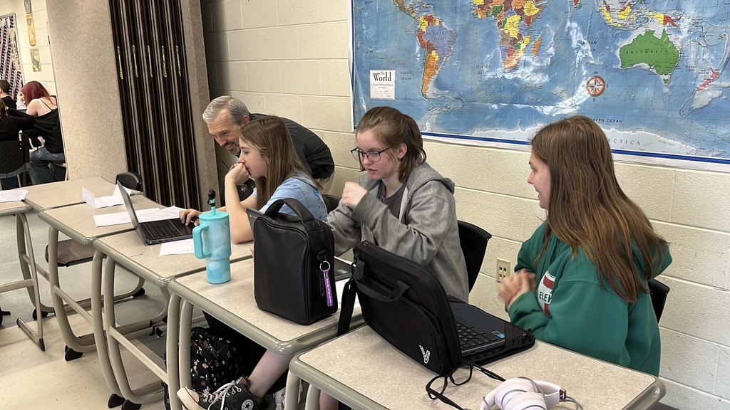 Students vote in a March Madness-themed history project. A teacher helps.