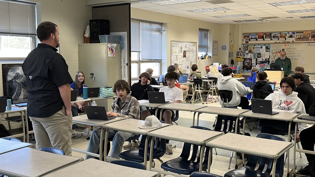 A teacher introduces a March Madness-themed history project to students.
