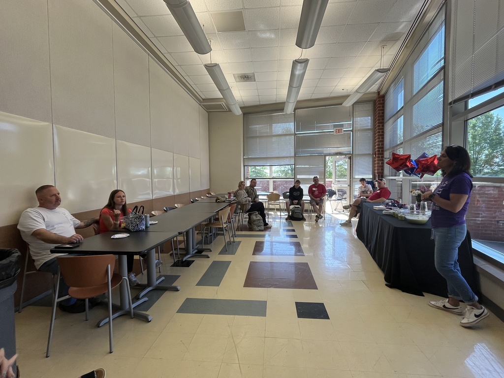 A woman talks to a room of military personnel and their teens.