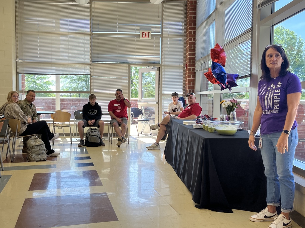 A woman talks to a room of military personnel and their teens.