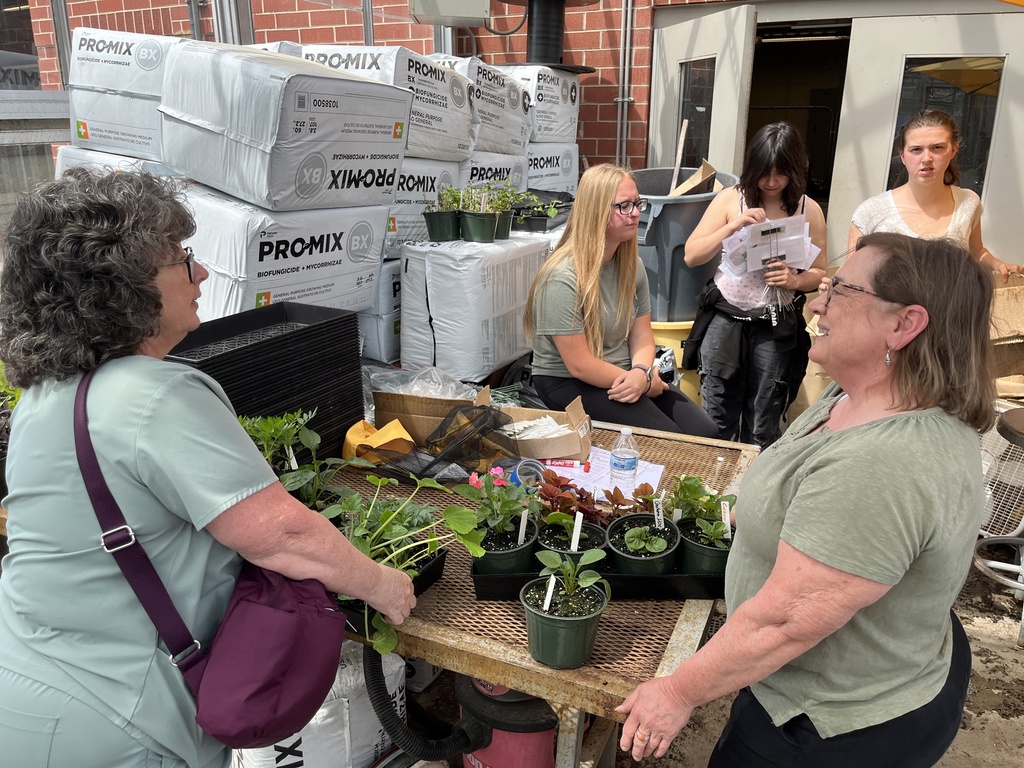 Women purchase plants at a plant sale. 