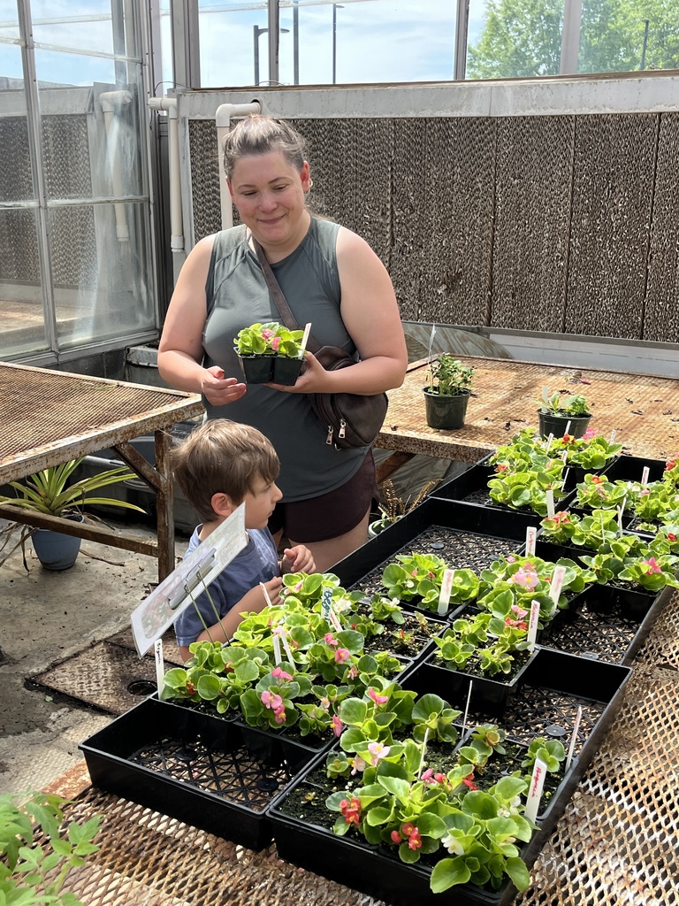 A woman and child browse plants  at a plant sale.