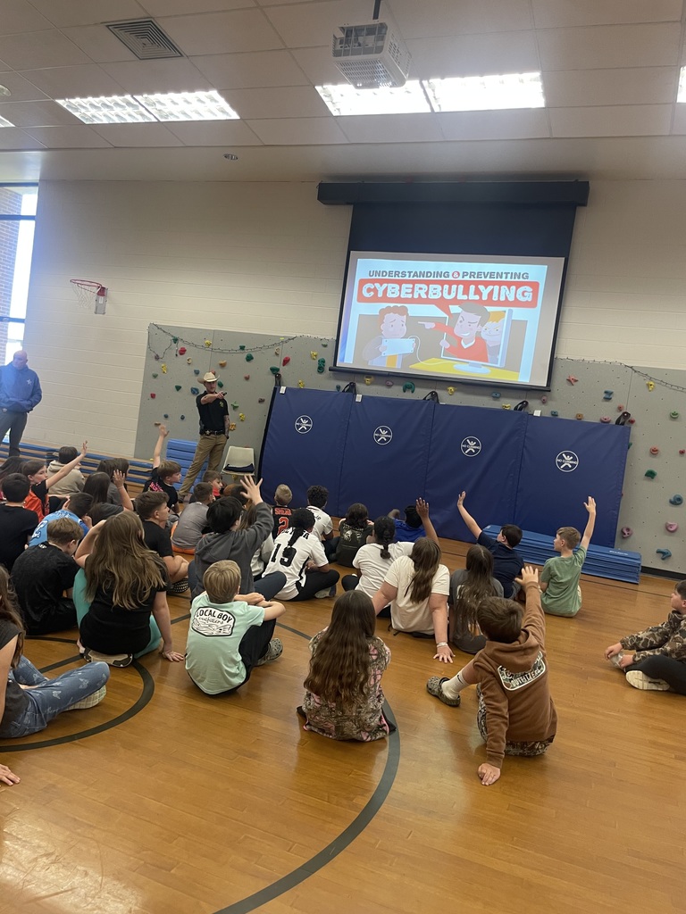 Detectives speak to a group of students about cybersecurity in a school assdembly. 