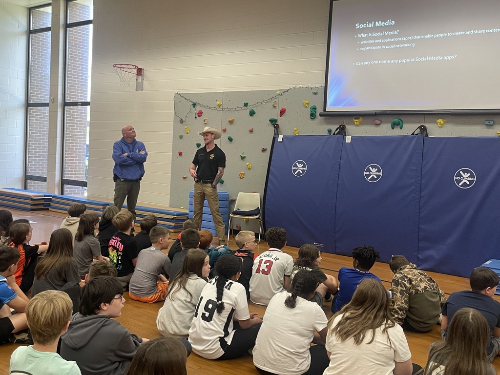 Detectives speak to a group of students about cybersecurity in a school assdembly. 