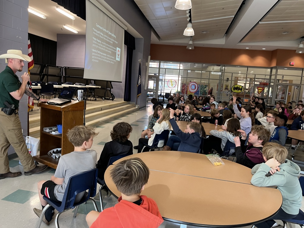 A detective speaks to a group of students about cybersecurity in a school assdembly. 