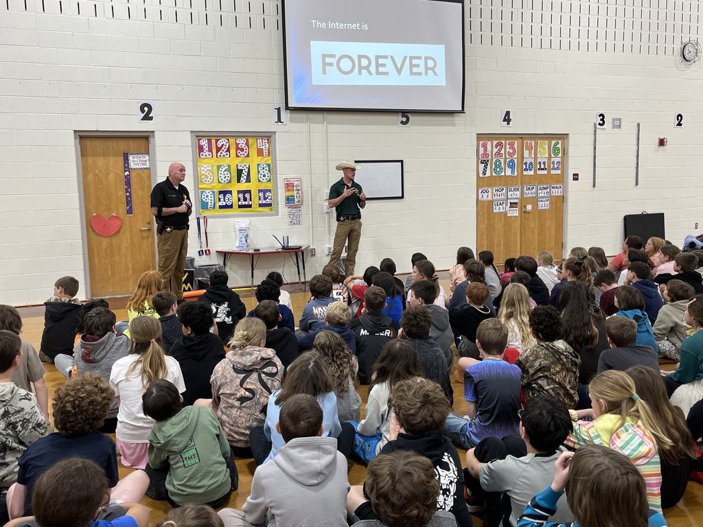 Detectives speak to a group of students about cybersecurity in a school assdembly. 