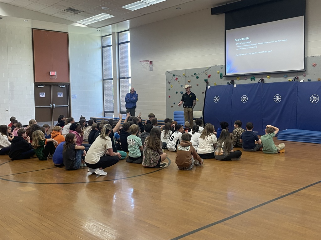 Detectives speak to a group of students about cybersecurity in a school assdembly. 