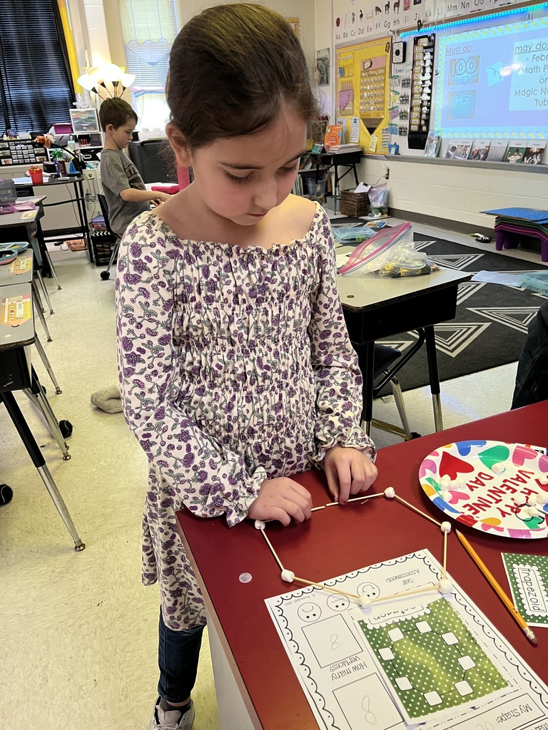 A student uses marshmallows and toothpicks to build a geometric shape.