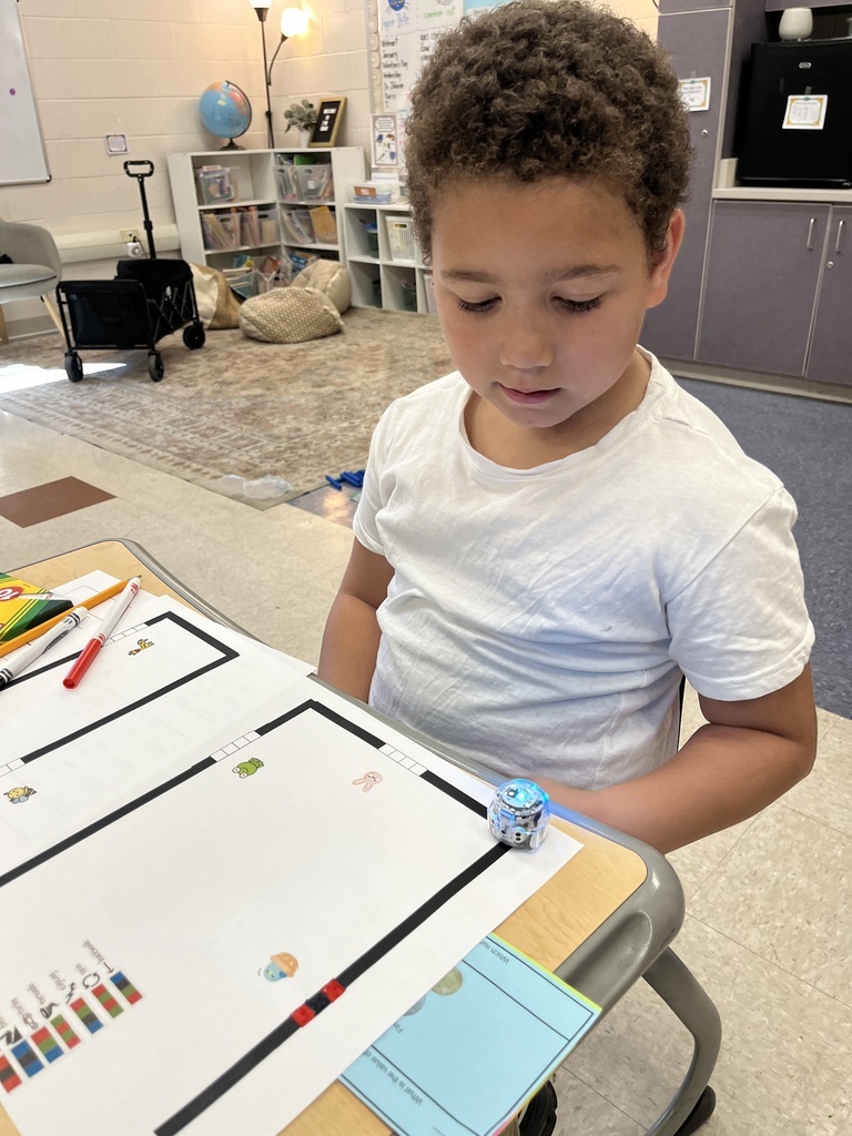 A child tests an Ozobot using data from a math worksheet he completed to code the robot.
