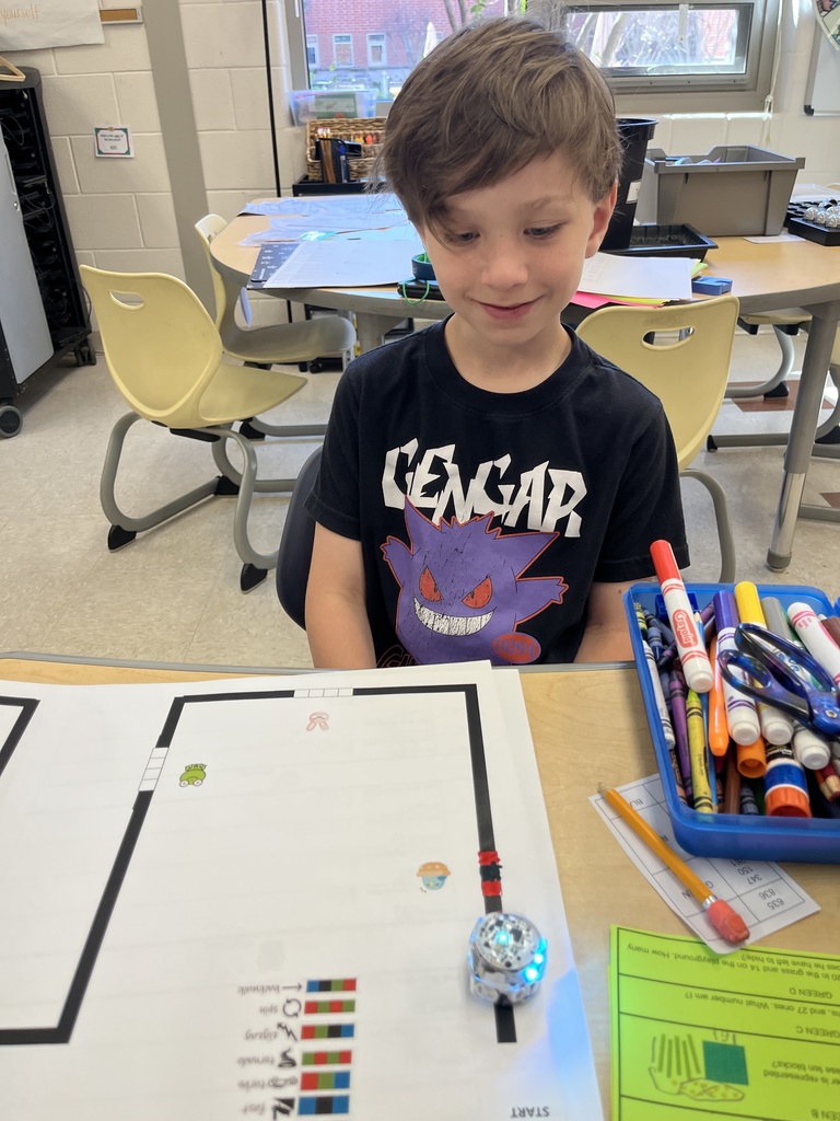 A child tests an Ozobot using data from a math worksheet he completed to code the robot.
