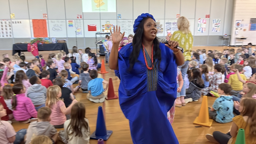 An African storyteller leads a school assembly in an elementary gym and uses student volunteers.