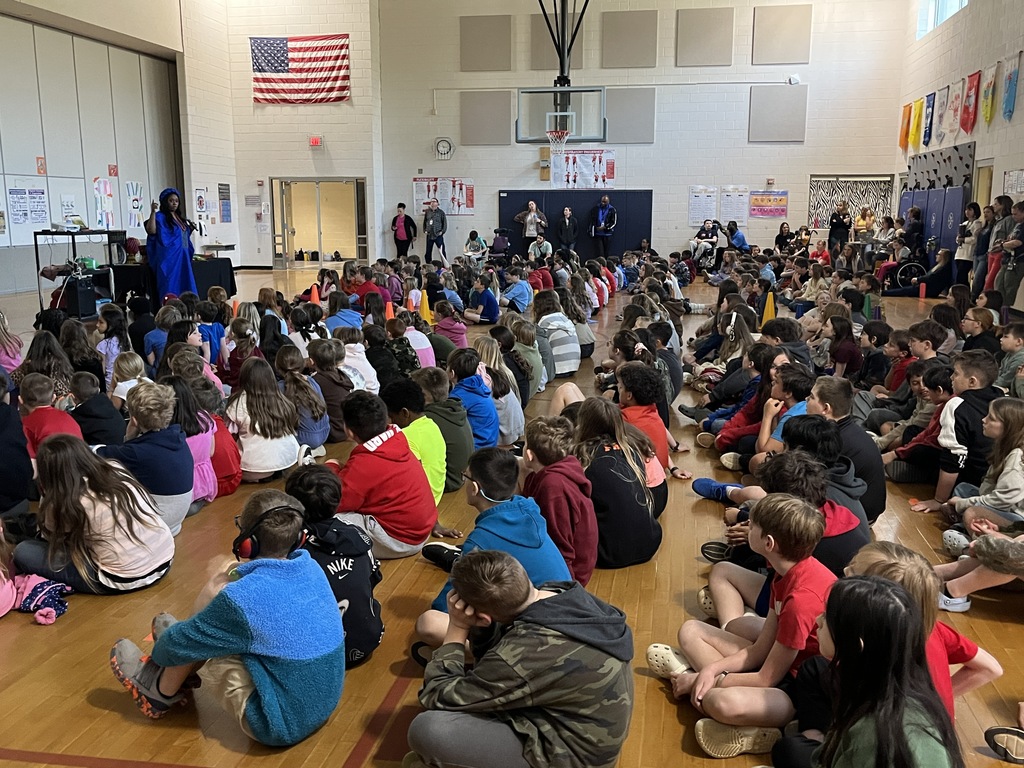 An African storyteller leads a school assembly in an elementary gym.