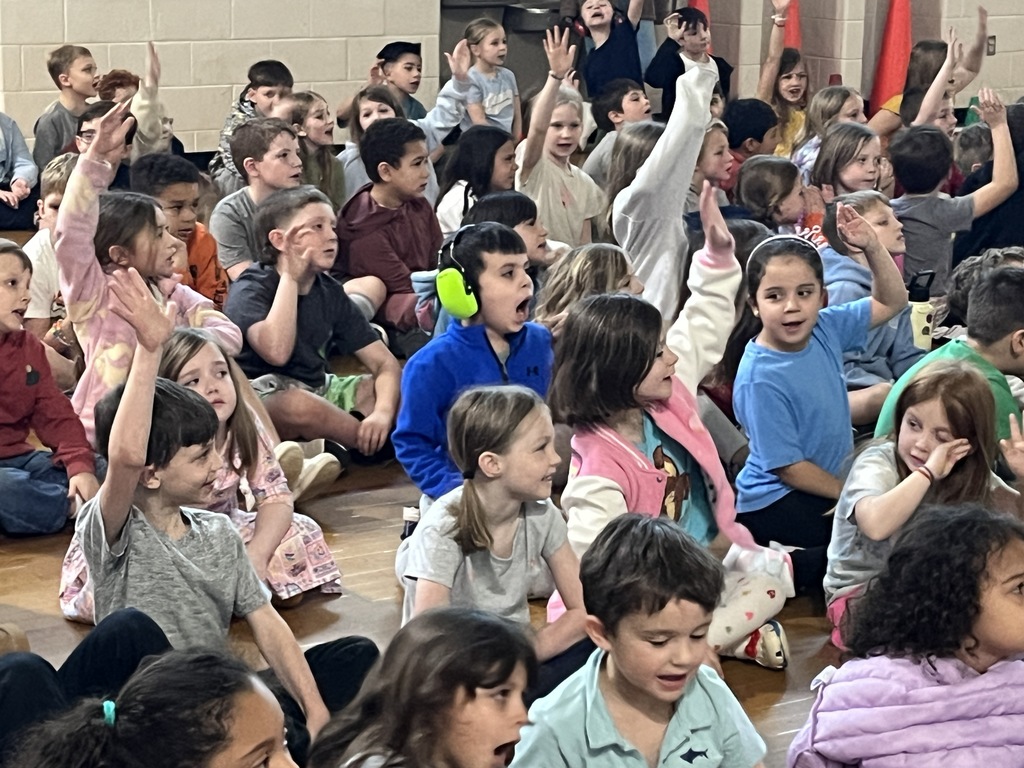 Students participate in  a school assembly in an elementary gym with an African storyteller.