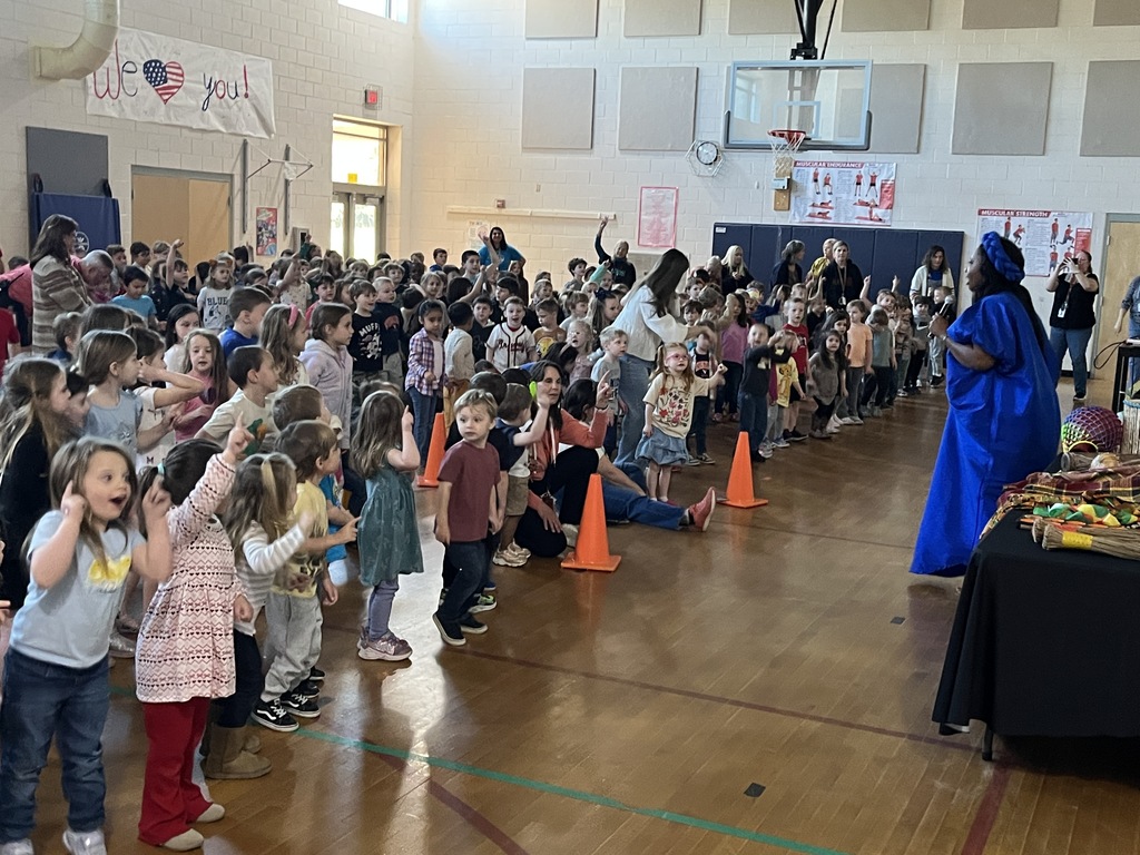 An African storyteller leads a school assembly in an elementary gym.