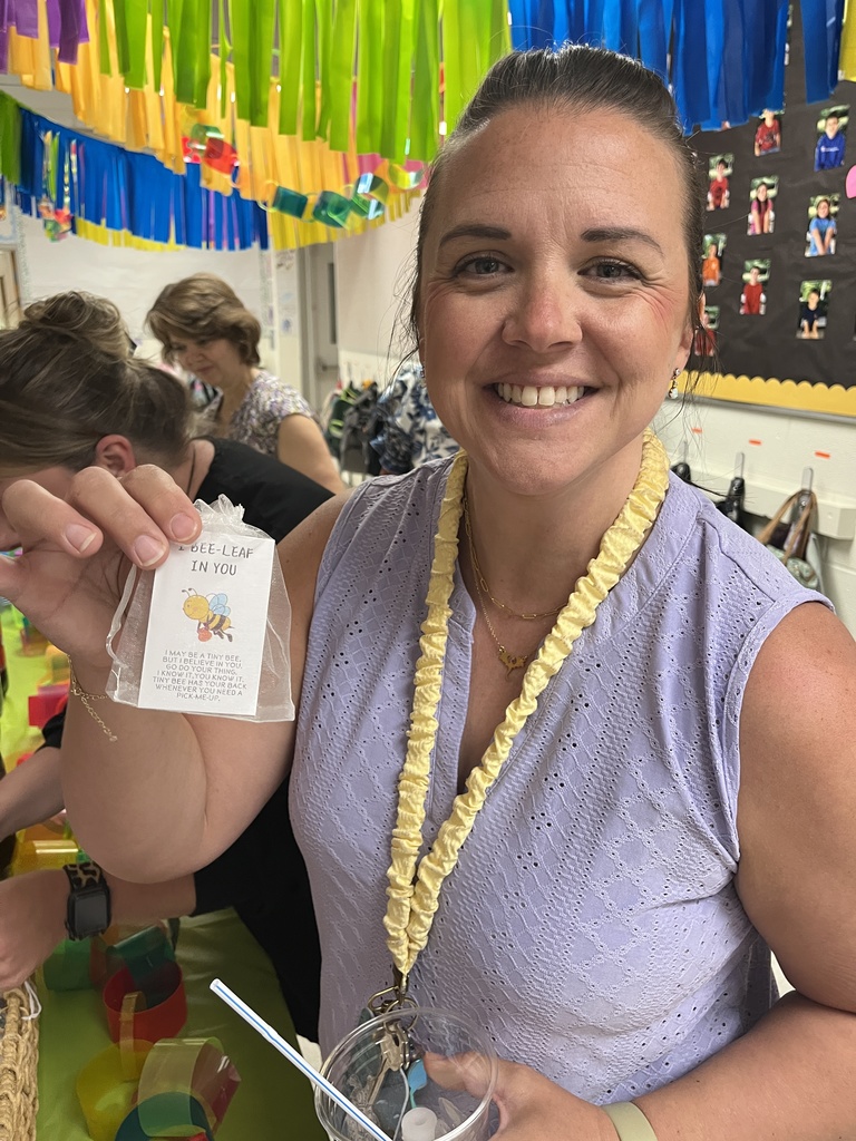 A staff member holds up a tiny plastic pet while other staff make drinks at a refresh station created by students.