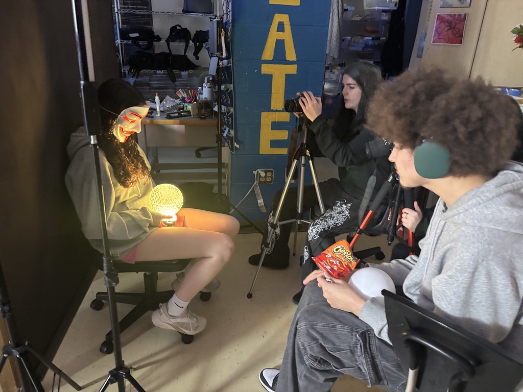Three students work together to create an artistic portrait photograph.