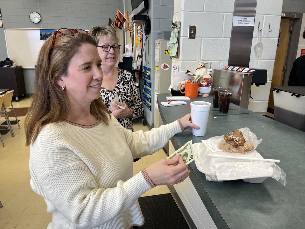 Two school employees pick up their meals from  a student cafe.
