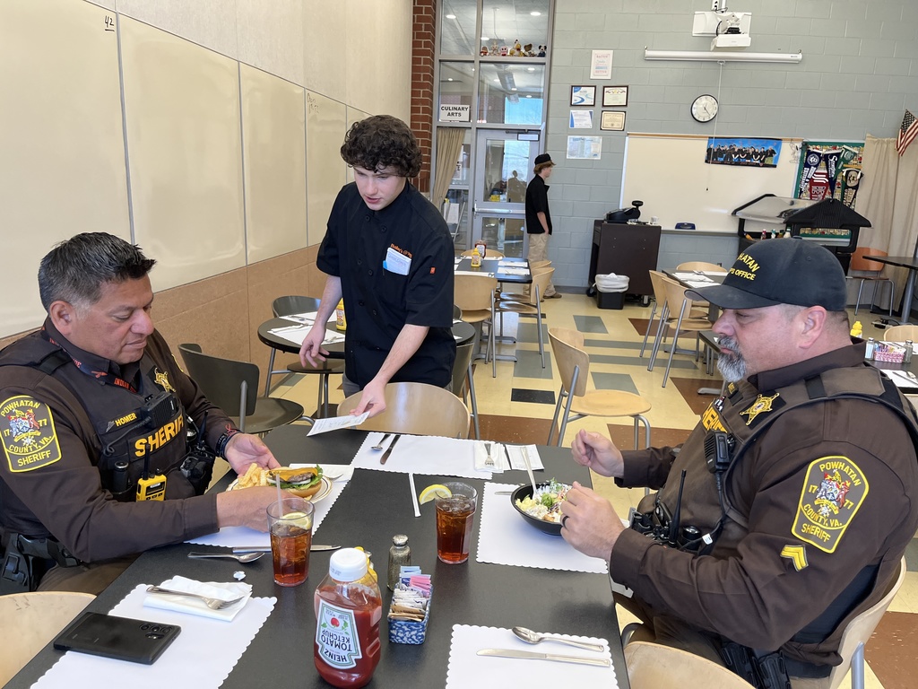 A student waiter serves lunch to two deputies.