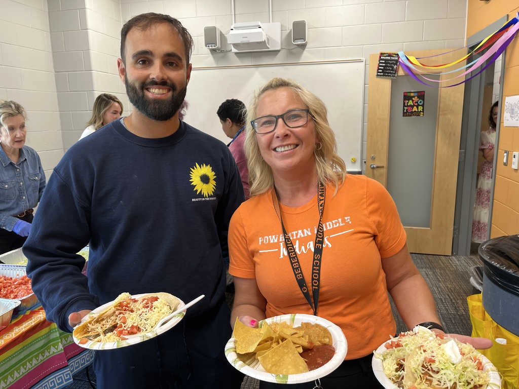 Two staff members pose for a photo at a staff appreciation taco bar at a school.