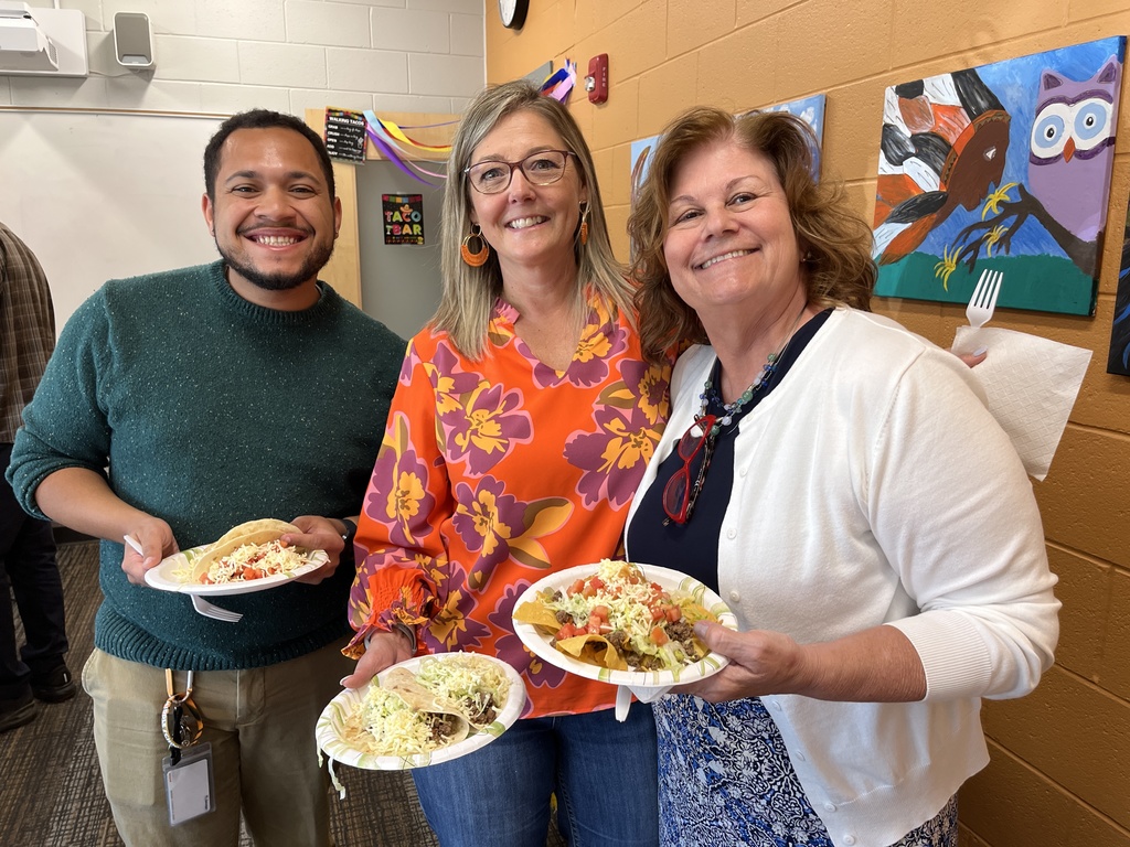 Three staff members pose for a photo at a staff appreciation taco bar at a school.