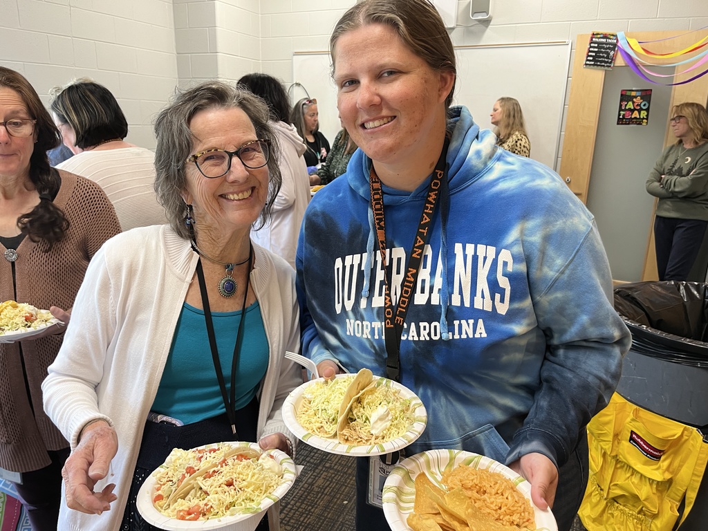 Two staff members pose for a photo at a staff appreciation taco bar at a school.