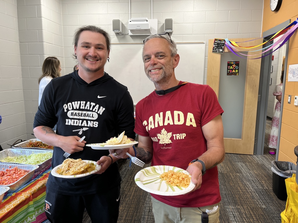 Two staff members pose for a photo at a staff appreciation taco bar at a school.