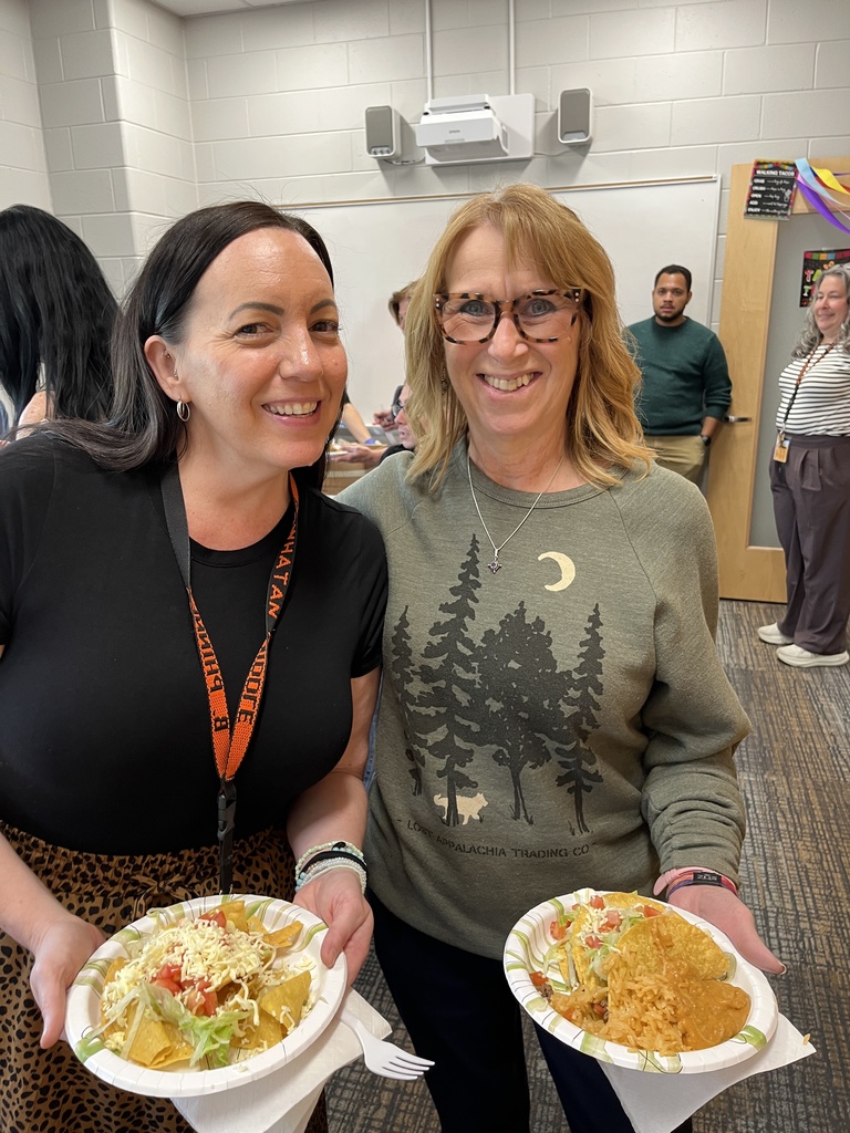 Two staff members pose for a photo at a staff appreciation taco bar at a school.