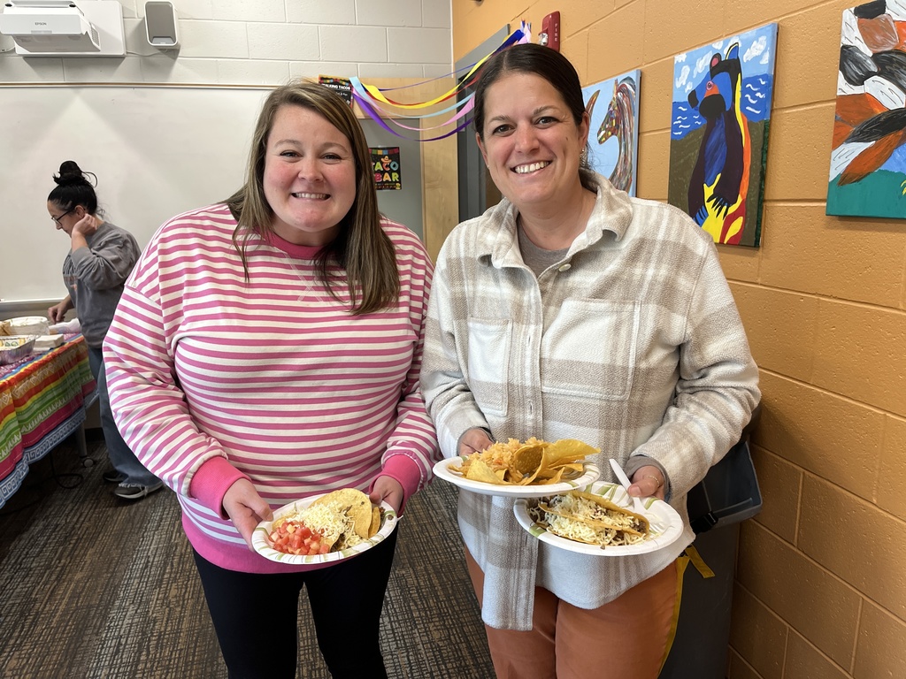 Two staff members pose for a photo at a staff appreciation taco bar at a school.