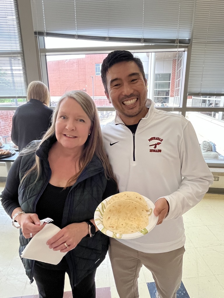 Two staff members pose for a photo at a staff appreciation taco bar lunch.