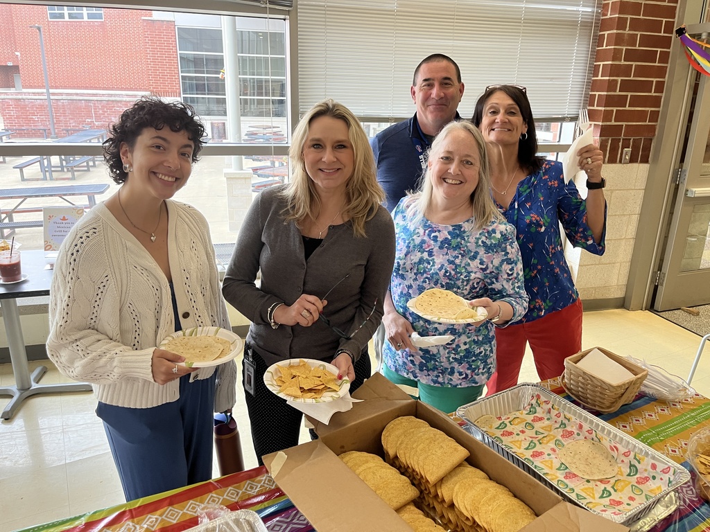 Five staff members pose for a photo at a staff appreciation taco bar lunch.