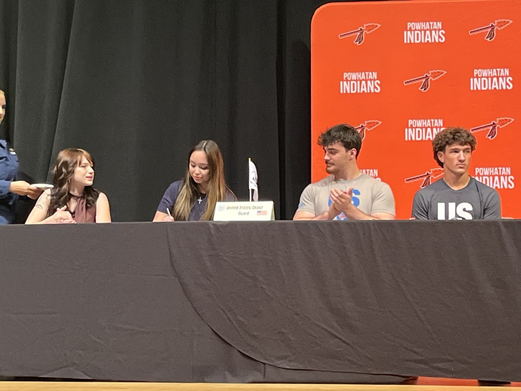 A student signs a letter of intent at a military signing day ceremony.
