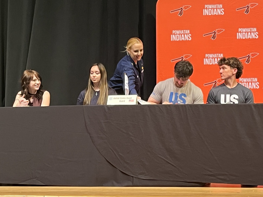A student signs a letter of intent at a military signing day ceremony.