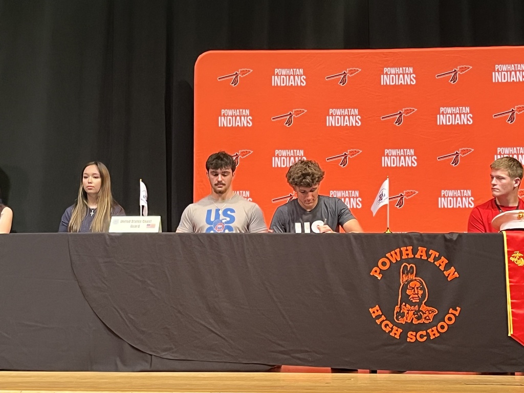 A student signs a letter of intent at a military signing day ceremony.